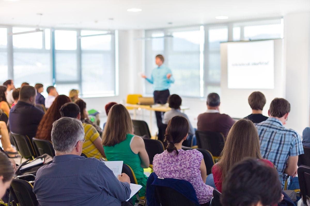 Professionals in a classroom listening to instructor's lecture.